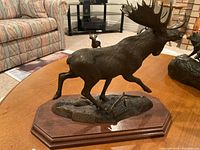 Full front view of metal moose sculpture on wooden base