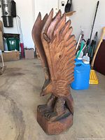 Front view of carved wooden eagle sculpture with wings raised, base and crack visible