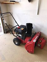 Left-side view of snowblower showing handle, wheels and engine housing