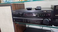 Pioneer VSX-D457 multi-channel audio/video receiver with control buttons, display screen, large volume knob, and remote controls on top.