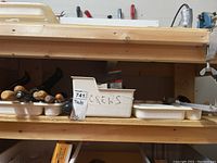 Shelf with wooden handles files and a white bin labeled 'screws' containing screws and other small hardware.