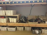Wide view of wooden shelf with power tools and labeled plastic bins