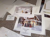 Two Walter Campbell winter scene prints showing certificates of edition and signatures, lying on a carpeted floor.