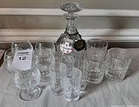 Full view of all items in the crystal barware set including decanter, glasses, and bottle necklaces.