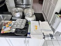Full view of baking pans and baker's cloths on kitchen counter showing entire lot.