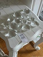 Multiple clear glass crystal diamond-shaped prisms arranged on a white wooden table.