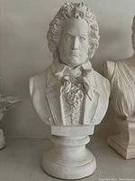 Front view of bust sculpture showing detailed hair curls and serious facial expression with detailed period clothing.