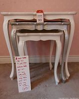 Three nested vintage tables showing white painted small and large tables and a distressed silver medium table with scalloped aprons and cabriole legs.
