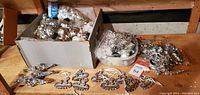 Multiple boxes and containers filled with assorted silver Christmas tree ornaments including hanging pieces and small figurines spread out on table