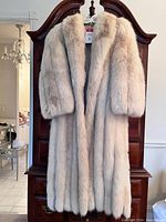 Full front view of the full-length fox fur coat hanging