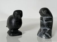 Front view of both stone carvings, bird on left and seal upright to right, showing shape and surface condition.