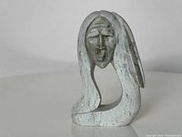 Front view showing stylized face and flowing hair