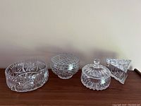 Front view of all four crystal bowls, showing shapes and presence of lids and metal mesh