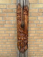 Close-up view of the three carved faces stacked vertically on the wooden post