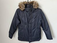 Front view of girls' navy blue down jacket with hood trimmed in faux fur, showing zip closure and front pockets.