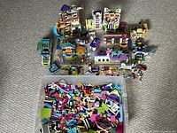 Overview showing the built LEGO Friends buildings arranged above a clear bin full of loose LEGO pieces.