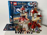 Photo showing the complete built Lego Harry Potter 'Attack on the Burrow' 75980 set with box and all minifigures in front.