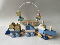 Front view of the wooden train and Janod boat bead maze toy on white background.