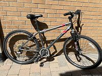 Full side view of the Norco Storm mountain bike showing the 17-inch aluminum frame, saddle, pedals, tires, and handgrips against a brick wall.