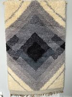 Full view of the rectangular rya rug featuring a central diamond pattern in gradients of grey to black and cream background