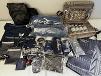 Photo of assorted airline amenity items, toiletry bag, and leather crossbody bag arranged on white surface showing Air Canada and Air Transat logos clearly visible on pillows, sleep masks, and bags.