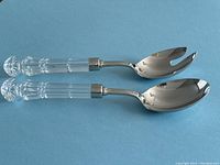 Pair of Waterford Lismore crystal handle salad spoons on blue background, showing full length of handles and metal heads