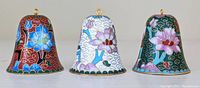 Front view of the set of three cloisonné bells showing red, white, and green color bases with floral designs and gold gilt detail.