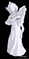 Full view of the white porcelain angel figurine playing the harp showing the flowing gown and harp with string details.
