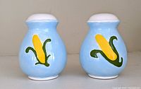 Front view of Jan Deshais handmade blue pottery salt and pepper shakers with hand-painted corn on the cob design