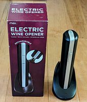 Photo of Meilo Electric Wine Opener with its recharging base and packaging box showing external product and features.