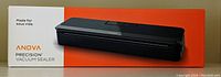 Image of the front of the boxed Anova Precision Vacuum Sealer in black with orange and white packaging showing device photo and branding