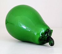 Side view of vintage green Murano blown glass pear, showing the intact round body and the broken stem.