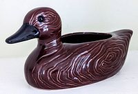Photo showing glossy brown ceramic mid-century styled duck planter with stylized feather patterns, black beak and eyes.
