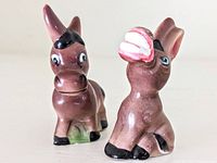 Front and side view of two mid-century ceramic donkey salt and pepper shakers with brown glaze and black hooves, showing their size and condition.