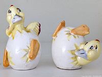 Pair of vintage ceramic duck salt and pepper shakers viewed laying on their sides showing shape, paint details and condition
