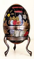 Front view of the vintage decorative brass egg trinket box on stand showing multicolor floral designs on black background.