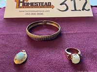 Overhead shot of all three pieces on purple cloth with seller card