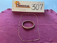 Overview of bracelet and chain laid out on cloth beneath lot number sign