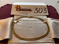 Full view of herringbone necklace laid flat on satin and burgundy fabric