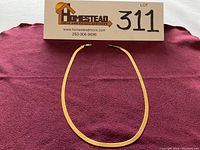 Full view of the flat herringbone chain laid out on burgundy cloth under Homestead signage