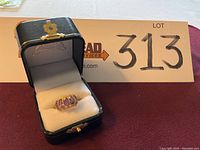 Ring displayed in an open presentation box, front view showing five purple stones.