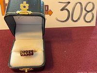 Ring displayed in black jewelry box with white interior and lot marker in background