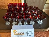Front view of the set of ruby red goblets on a table with a paper showing lot number 409.