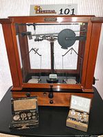 Front view of analytical balance in wooden and glass case with weights displayed