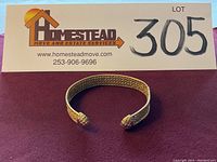 Front view of open cuff bracelet showing filigree band and decorative terminals.