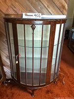 Front view showing curved glass, wooden vertical slats, and decorative carved wood on door top center, with key lock and lighting cord visible on side.