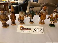 Lot of six German wooden smokers incense burner figurines displayed side by side on a table, ranging between 7.5 and 8.5 inches tall.