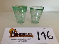 Pair of green swirl glass tumblers from Kosta Boda, showing the side angle and shape differences.