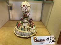 Front view of the porcelain musical centerpiece showing the hot air balloon with Santa Claus and village base