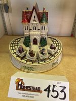 Front view of the Lenox holiday musical roller coaster figurine showing the snow-covered castle with red and green towers, track, and four roller coaster cars with festive characters.